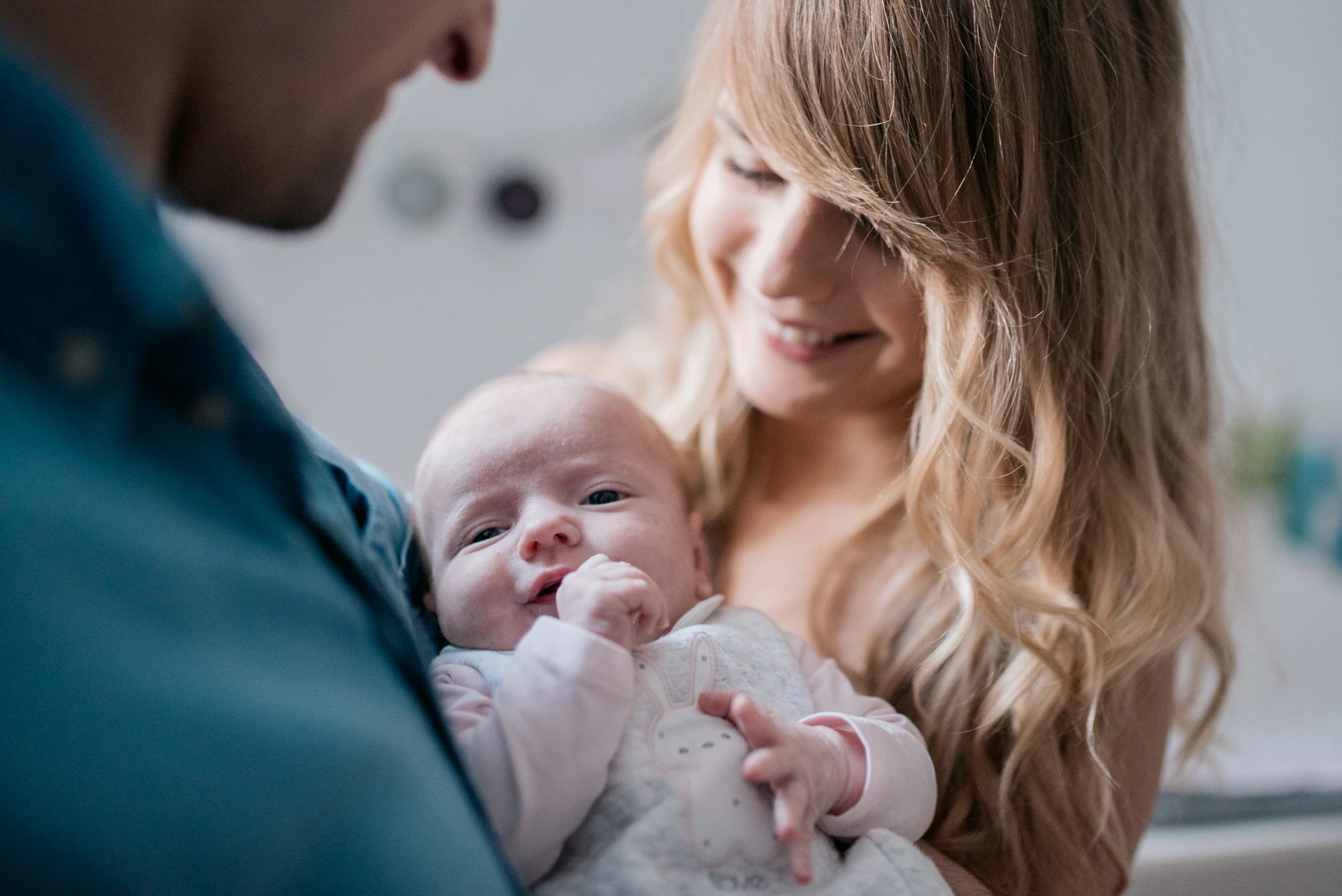 Jeunes parents tenant leur nouveau-né éveillé dans leurs bras lors d'une séance photo lifestyle